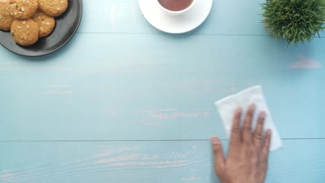 cleaning a light blue wooden table with a napkin