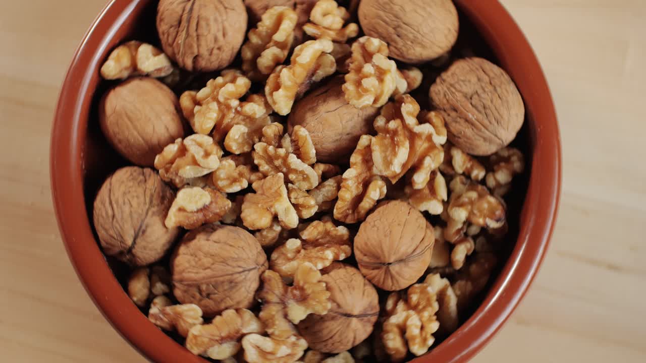 Mix of walnuts rotating in red plate top view. Walnut in shell, walnut without shell. Peeled nuts. Healthy snacks. Product rich in minerals and vitamins.