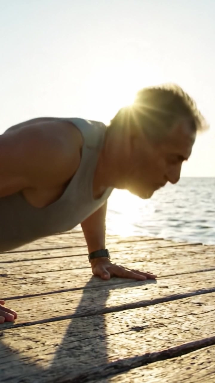 A Determined Individual Engages in Outdoor Push-Ups on a Wooden Dock as the Sun Sets Over Calm Waters, Emphasizing Commitment to Fitness and Well-Being