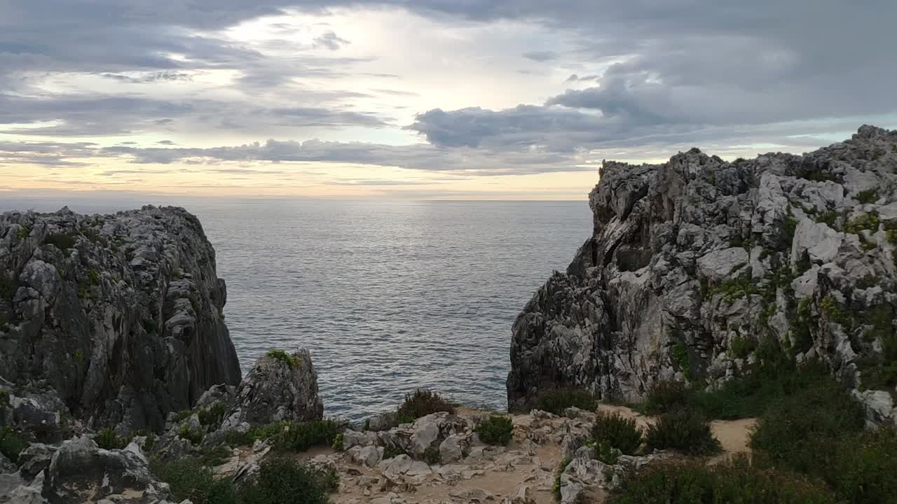 Rocky cliffs above calm sea at Guadamia and Tuzarrizu, Asturias, during sunset