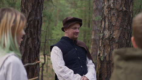 positive man and children in medieval clothes in forest