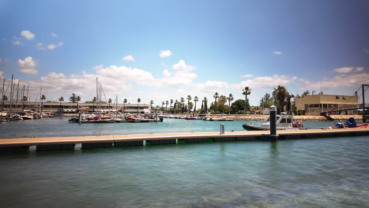timelapse: marina de lagos con barcos y puente peatonal bajo un cielo azul claro en lagos, algarve, portugal