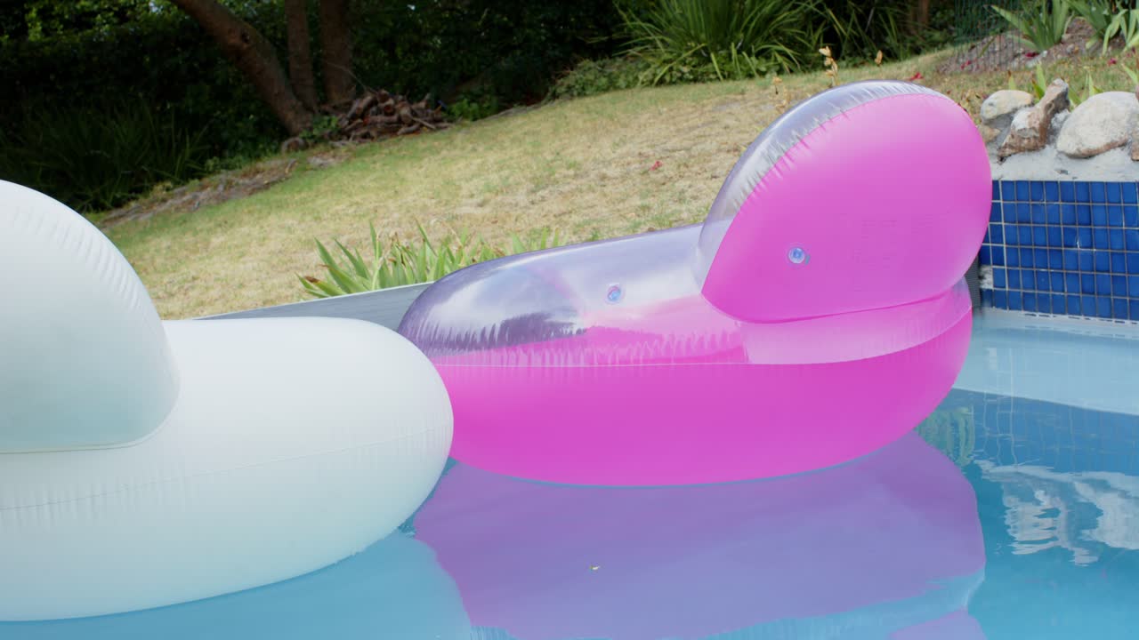 Mild breeze nudging hot pink pool float, drifting right and rotating head toward blue tiled coping