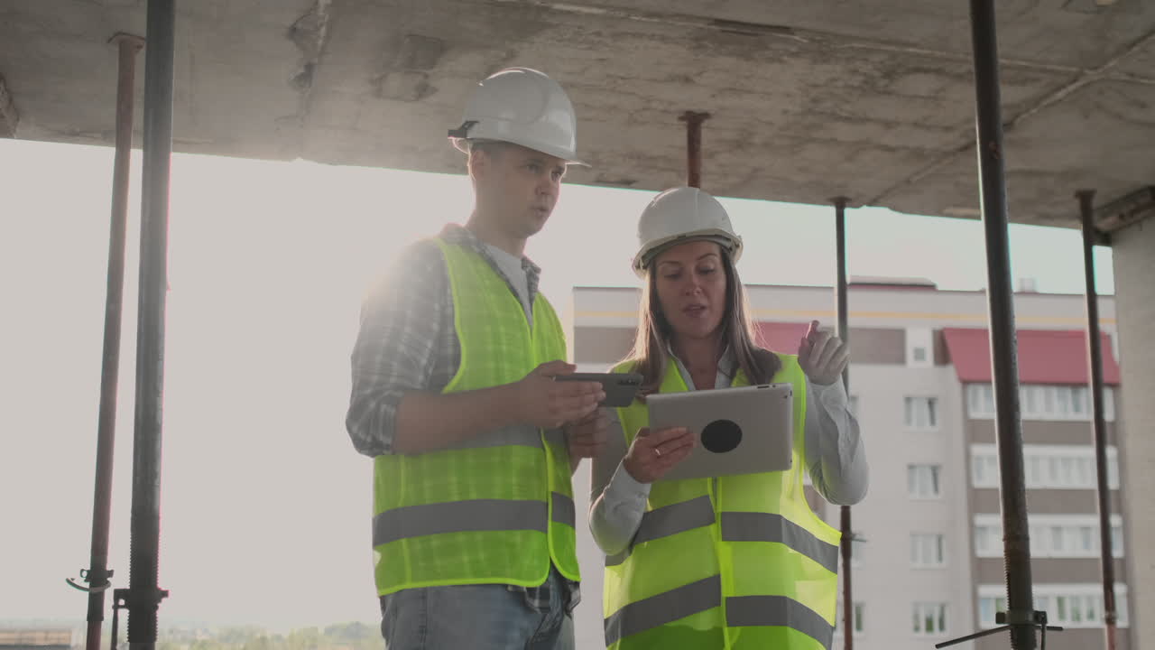 supervisor de un edificio en construcción hombre discutiendo con ingeniero diseñador mujer el progreso de la construcción y examina un plan de construcción.