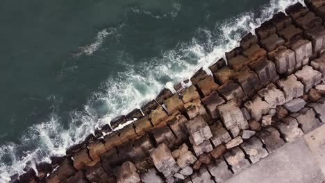 drone shot top view waves hitting the pier