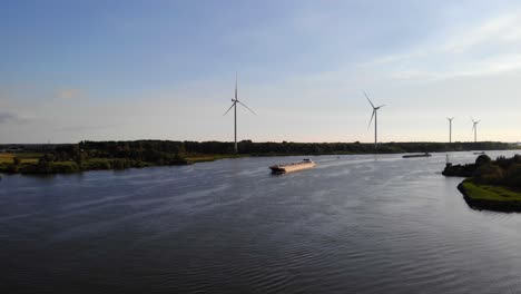 aerial over oude maas with somtrans x inland tanker travelling along oude maas with row of wind turbines in background
