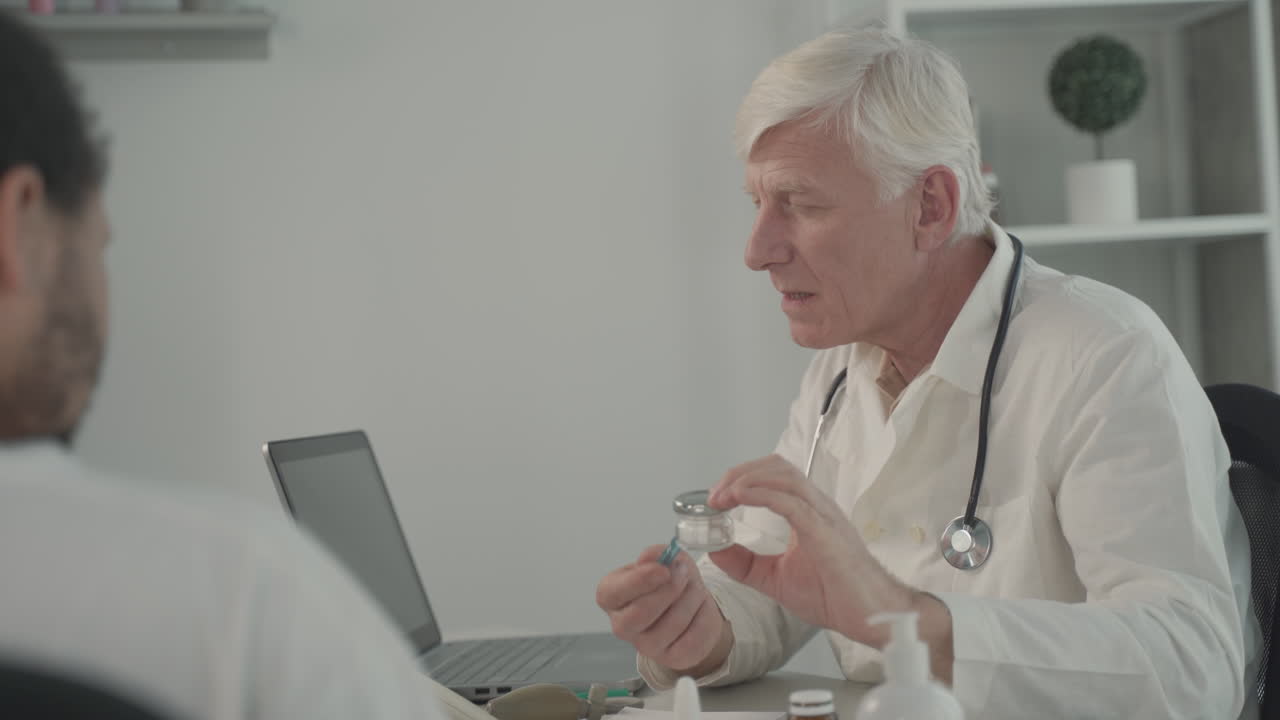 седовласый врач средних лет говорит о таблетках с пациентами