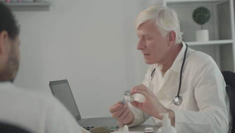 a grey haired, middle aged doctor talking about tablets to some patients