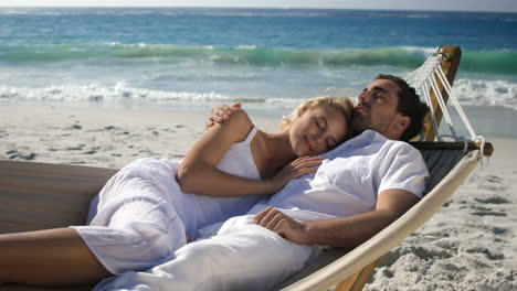 una pareja relajándose en una hamaca en la playa.