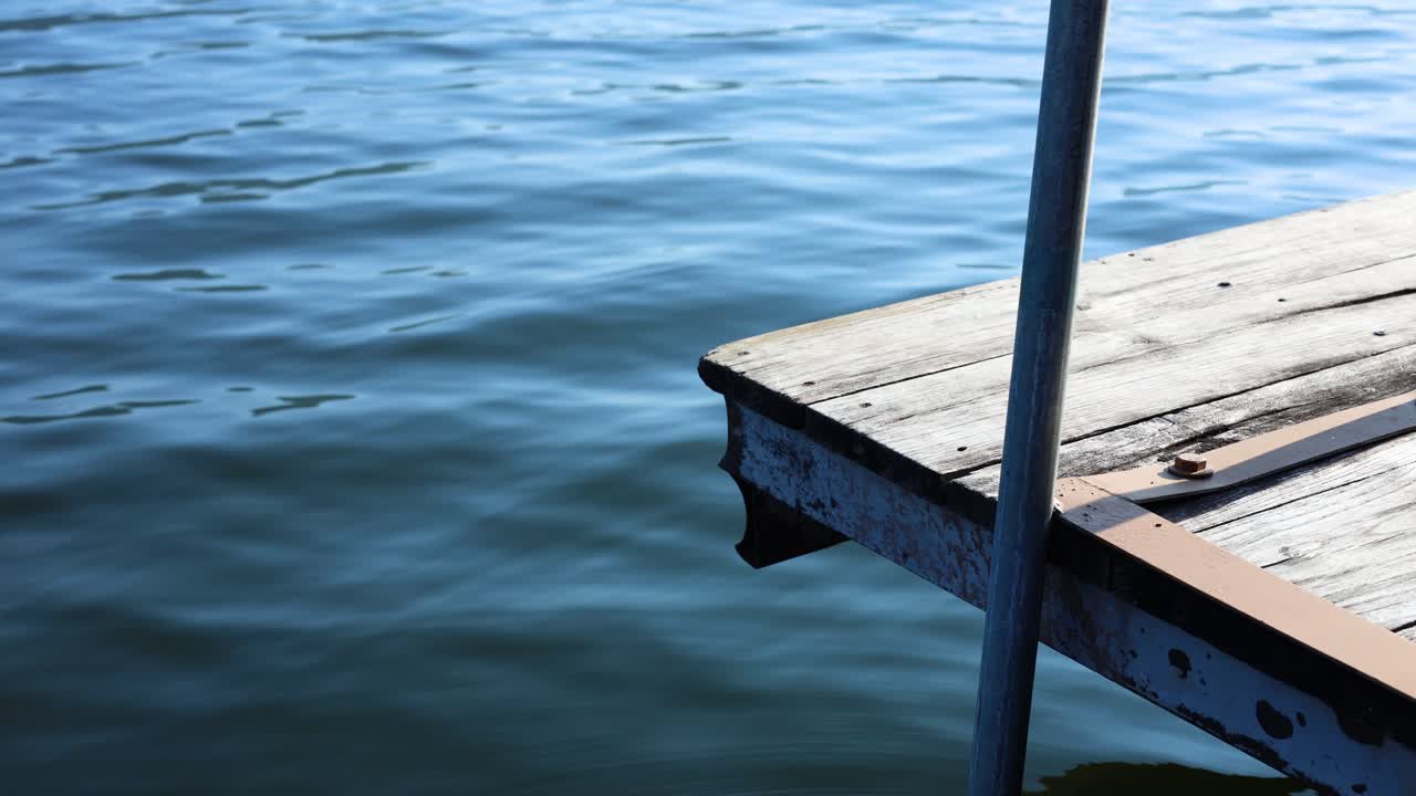 Wooden dock gently sways above tranquil blue water
