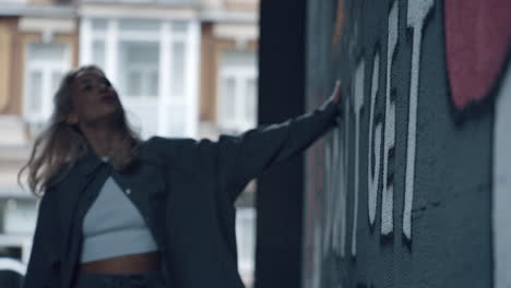 Girl looking graffiti wall at daytime in modern city background.