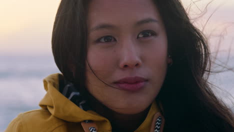 portrait of happy asian woman enjoying peaceful contemplation exploring carefree lifestyle relaxing on beach feeling positive at sunrise