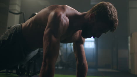 man doing push ups in a gym. exhaling and inhaling after push-ups and exercise. perfect for fitness and workout. young sports man performs pushups in the gym. the athlete is engaged in fitnes