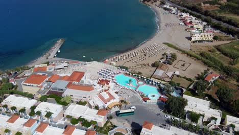 drone flying over beach resort view to pool and strand in greece on crete, sunshades on strand