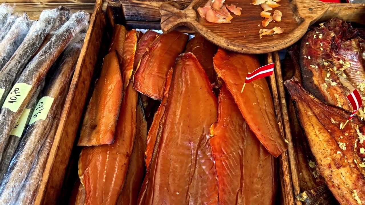 Casse di legno del mercato piene di filetti di pesce affumicato e pesce lungo confezionato sottovuoto, che mostrano prodotti ittici artigianali in una bancarella di cibo all'aperto