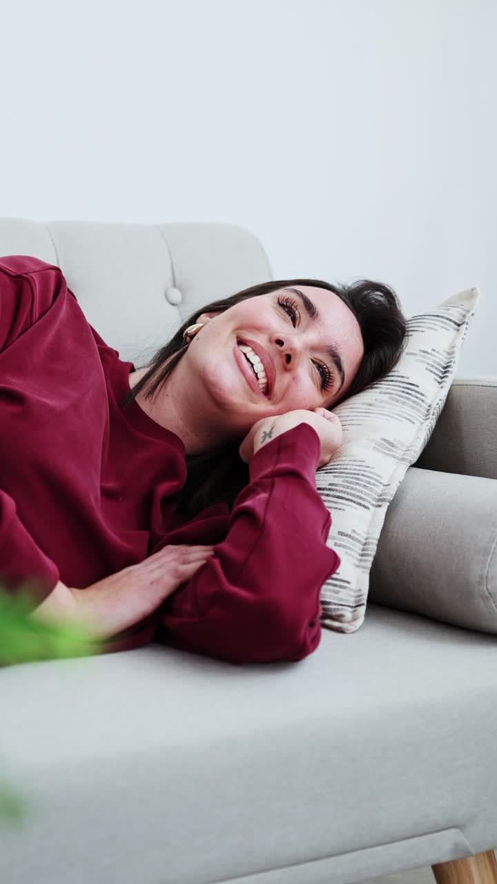 Giovane donna sorridente che si rilassa e si addormenta su un divano