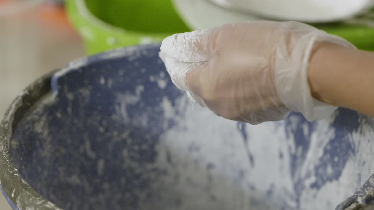 A hand wearing a protective glove sifts the plaster until it reaches the belly, which is then mixed with a hand mixer