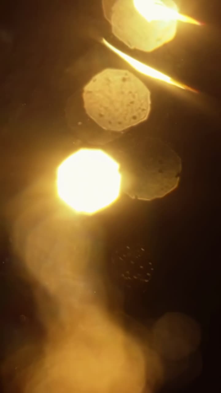 Video astratto con inquadratura ravvicinata, che cattura luci bokeh dorate in un ambiente scuro