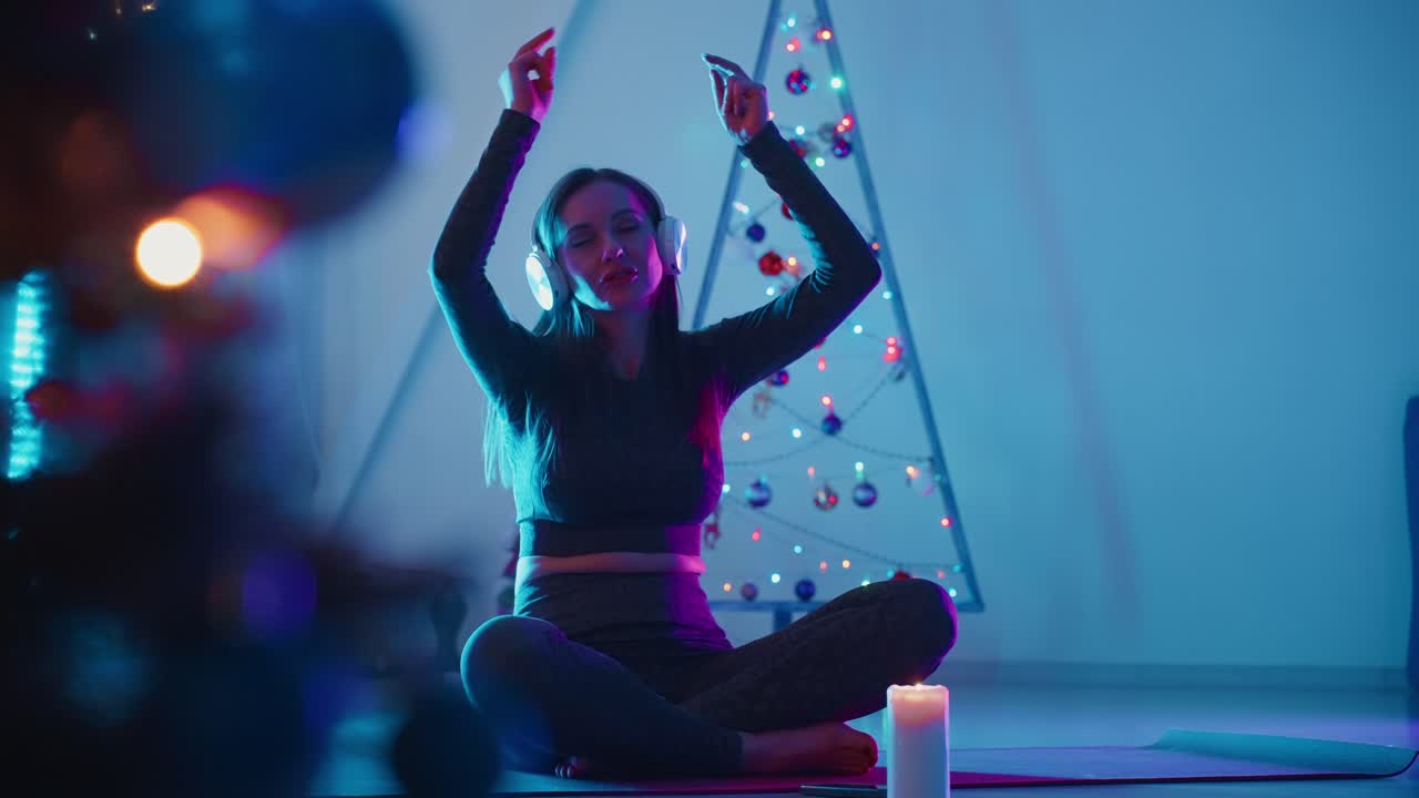 Woman meditating with headphones near a Christmas tree