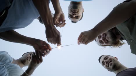 focused and smiling young people with burning sparklers