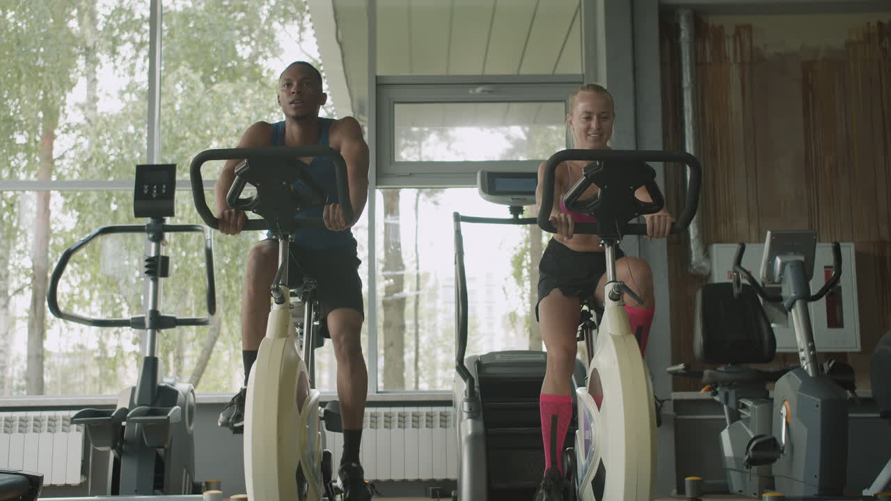 코카시안 여성 모니터와 체육관에서 운동하는 아프리카계 미국인 남자의 앞면.