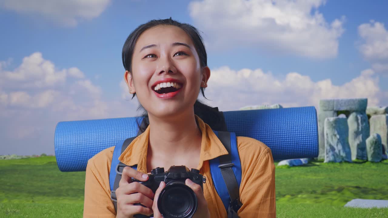 Close Up Of Asian Female Hiker With Mountaineering Backpack Smiling And Holding A Camera In Her Hands Then Looking Around While Traveling In Stonehenge