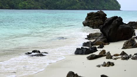 tropical island beach with turquoise water and rocks