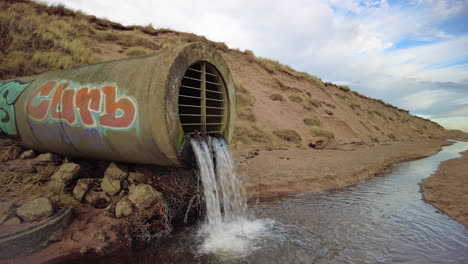 alcantarilla descargando agua en un arroyo en una playa