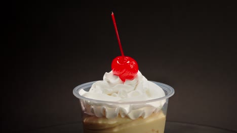 Vanilla-cream-cup-parfait-cherry-on-top-spinning-in-turntable-with-black-background-copa-nevada