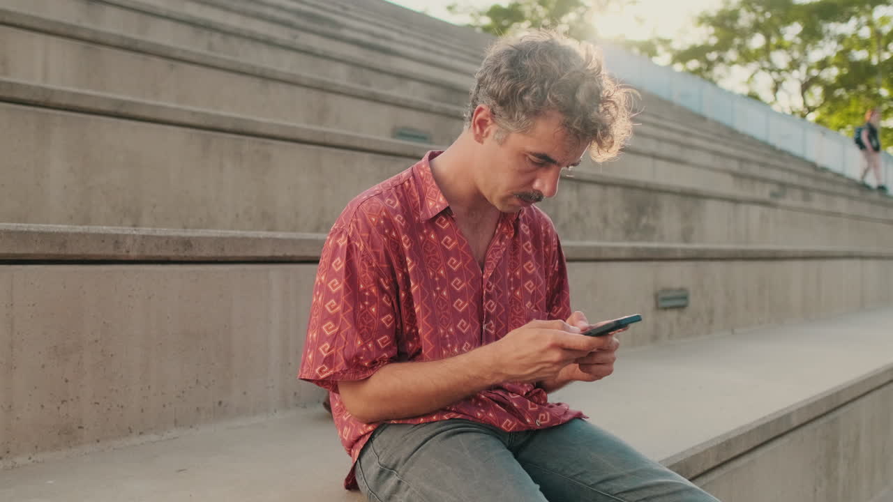 Young Man Using Smartphone While Sitting on Concrete Steps