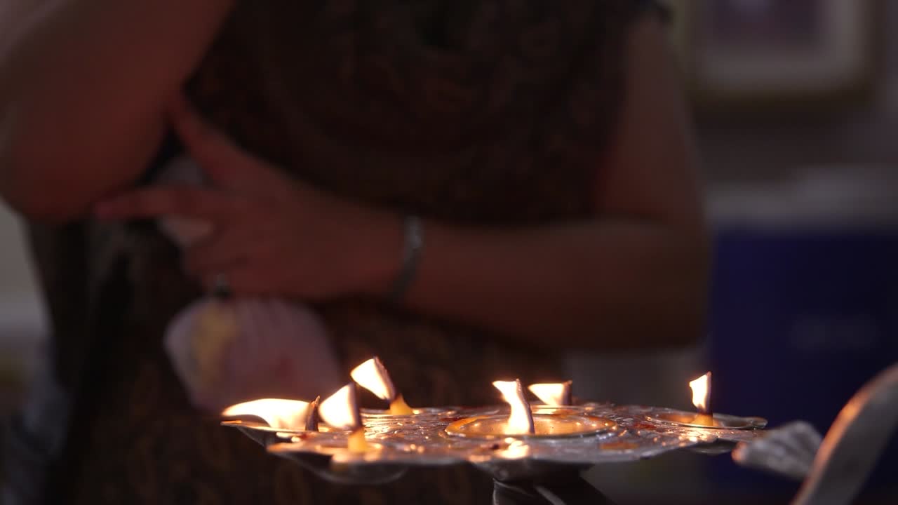 Hindu Women Fire Cleansing Hand with Candle Flames in Religious Ritual Ceremony in Temple
