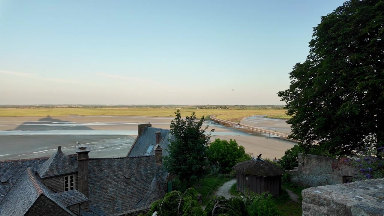 La marée montante déferle sur la baie du Mont Saint-Michel en fin d'après-midi, inondant le littoral exposé sous une chaude lumière crépusculaire et mettant en valeur l'un des paysages de marée les plus spectaculaires du monde.