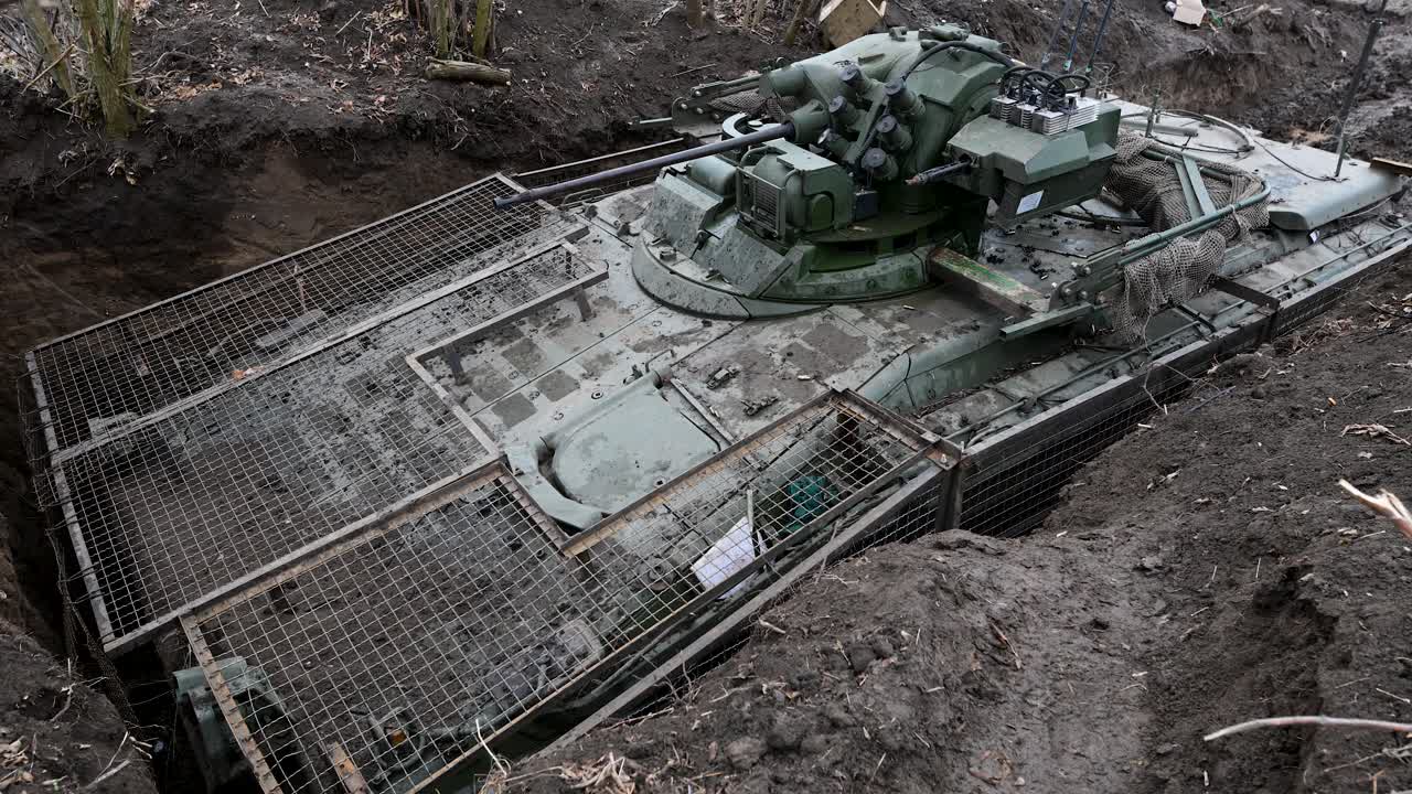 A Russian BMD-4M airborne IFV is concealed in a deep revetment on the Ukrainian front. It is fitted with extensive slat armor, a defense against the constant threat of drone attacks