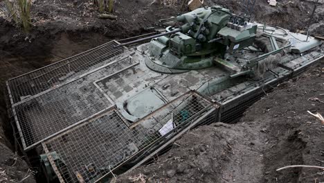 a russian bmd-4m airborne ifv is concealed in a deep revetment on the ukrainian front. it is fitted with extensive slat armor, a defense against the constant threat of drone attacks