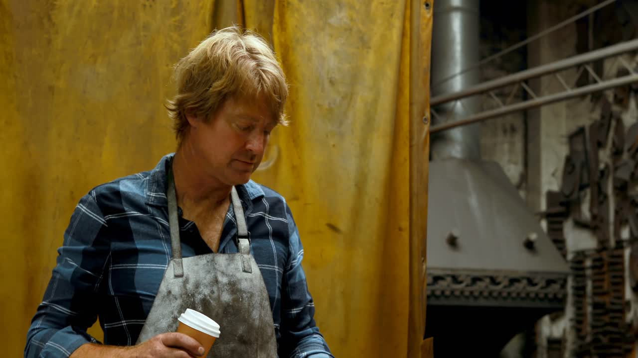 smid die koffie drinkt terwijl hij een mobiele telefoon 4k gebruikt