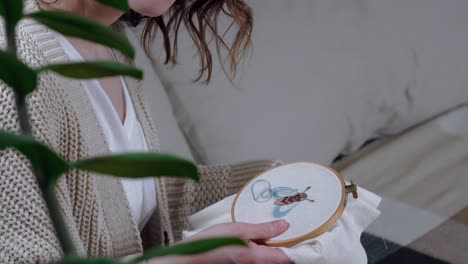 young woman holding loop with embroidered picture of a bee