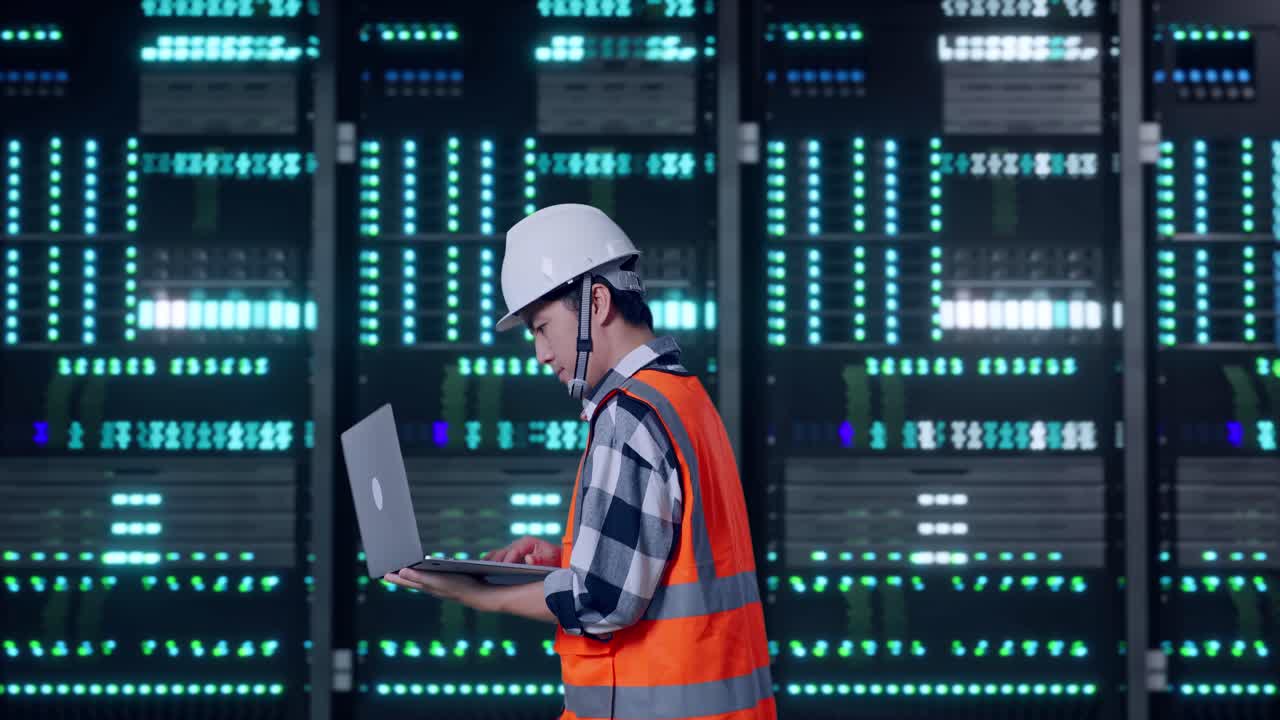 Side View of Asian Male Engineer Use Computer While Walking in Server Room Data Center