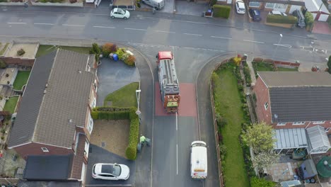 a bin lorry, refuse collection vehicle makes it way up the road as men load recycling bins into the waste compactor in a middle-working class area in the city