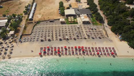 Aerial-shot-of-Myrtos-beach-seen-from-the-sea-full-of-beach-chairs,-horizontal-movement