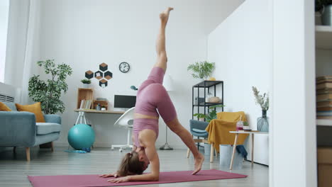 woman practicing headstand yoga pose at home