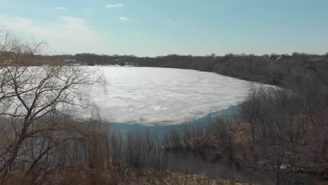 video de drones aéreos del lago susan en chanhassen minnesota volando a través de los árboles hasta el deshielo del agua del lago que retrocede