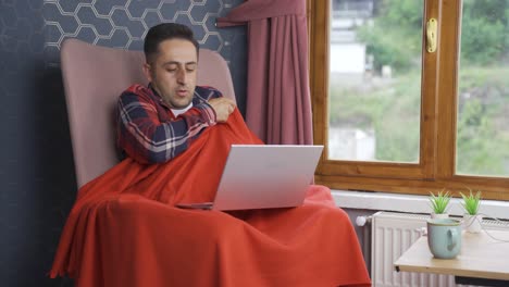 the man is cold and trying to use a laptop.