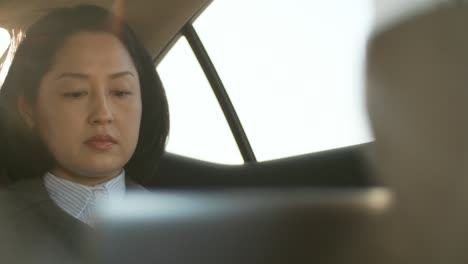 asian woman working on laptop in taxi