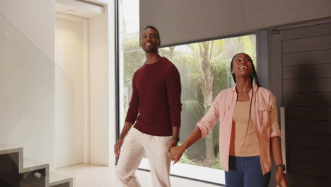 smiling young african american couple holding hands and exploring new home together