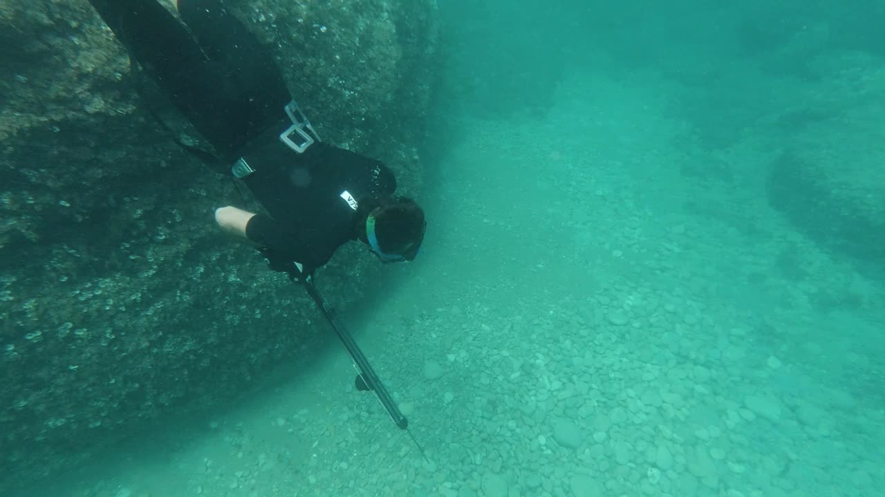 Spearfisher dives in apnea to the sea floor looking for fish in the mediterranean sea