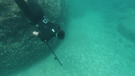 spearfisher dives in apnea to the sea floor looking for fish in the mediterranean sea