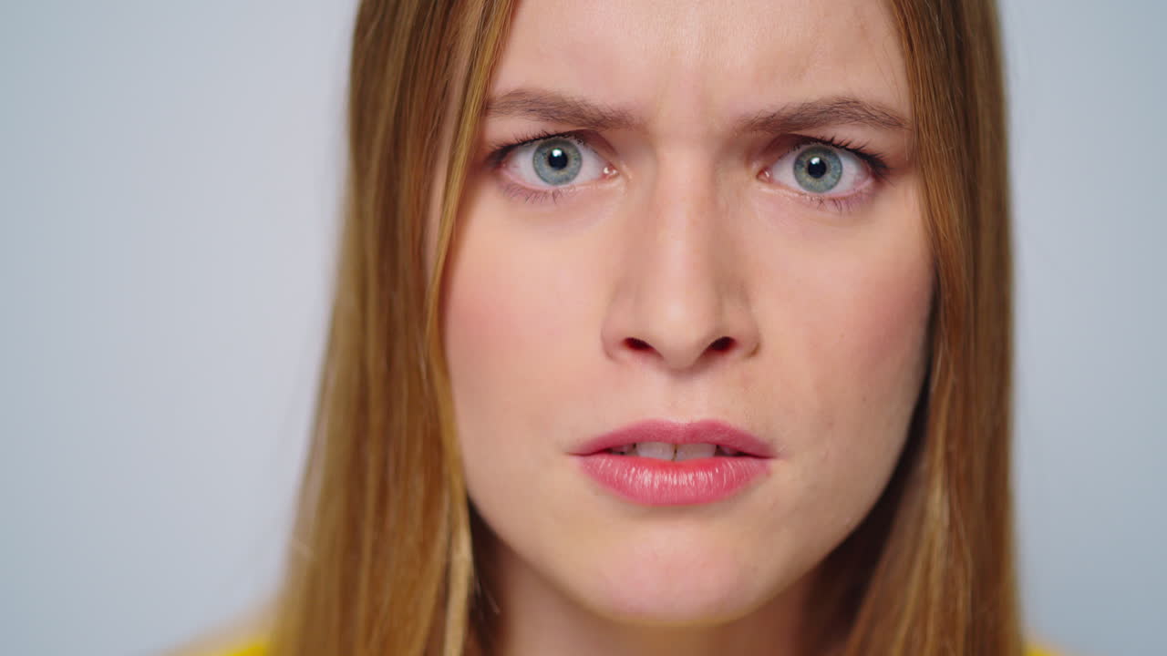Closeup angry woman shouting with aggressive emotion at camera in studio.