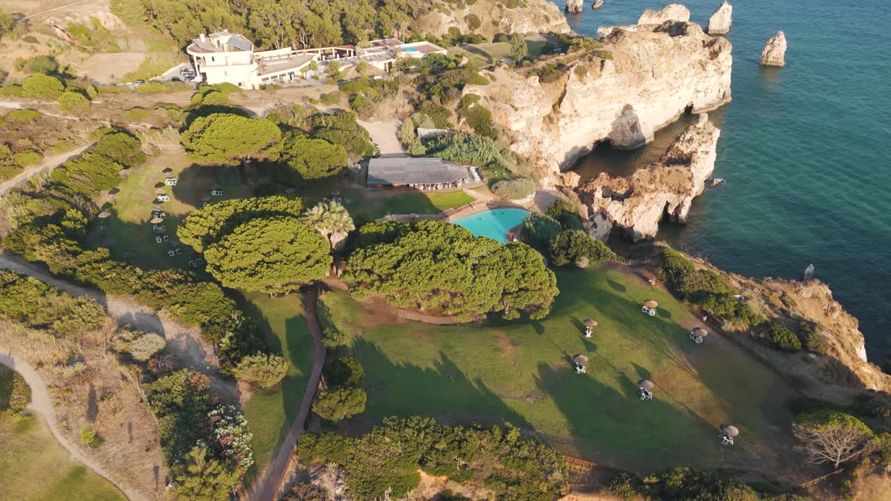 Aerial - dramatic cliffs and green leisure area meet ocean at Alvor in Algarve Portugal