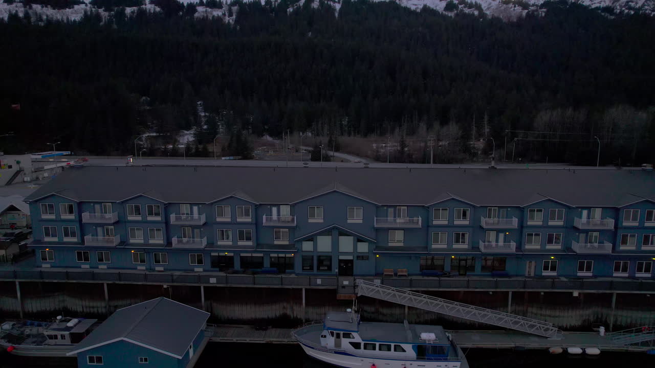 vista aérea de drones de derecha a izquierda del hotel harbour 360 en seward alaska con las montañas al atardecer