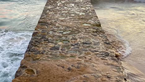 Steindeck-An-Einem-Strand-Mit-Türkisfarbenem-Meer-Mit-Felsen-Im-Vordergrund-Am-Strand-Von-Carcavelos